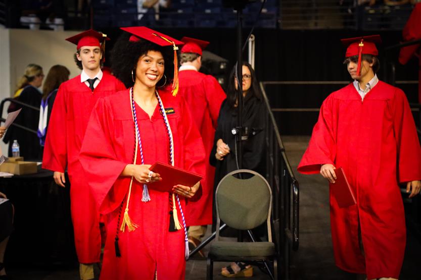 Students in red robes graduate